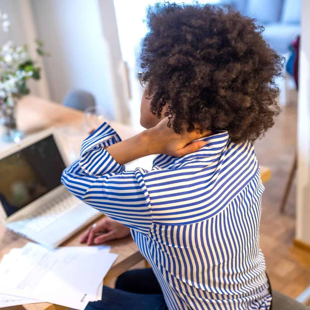 Woman sitting at desk holding her neck in pain
