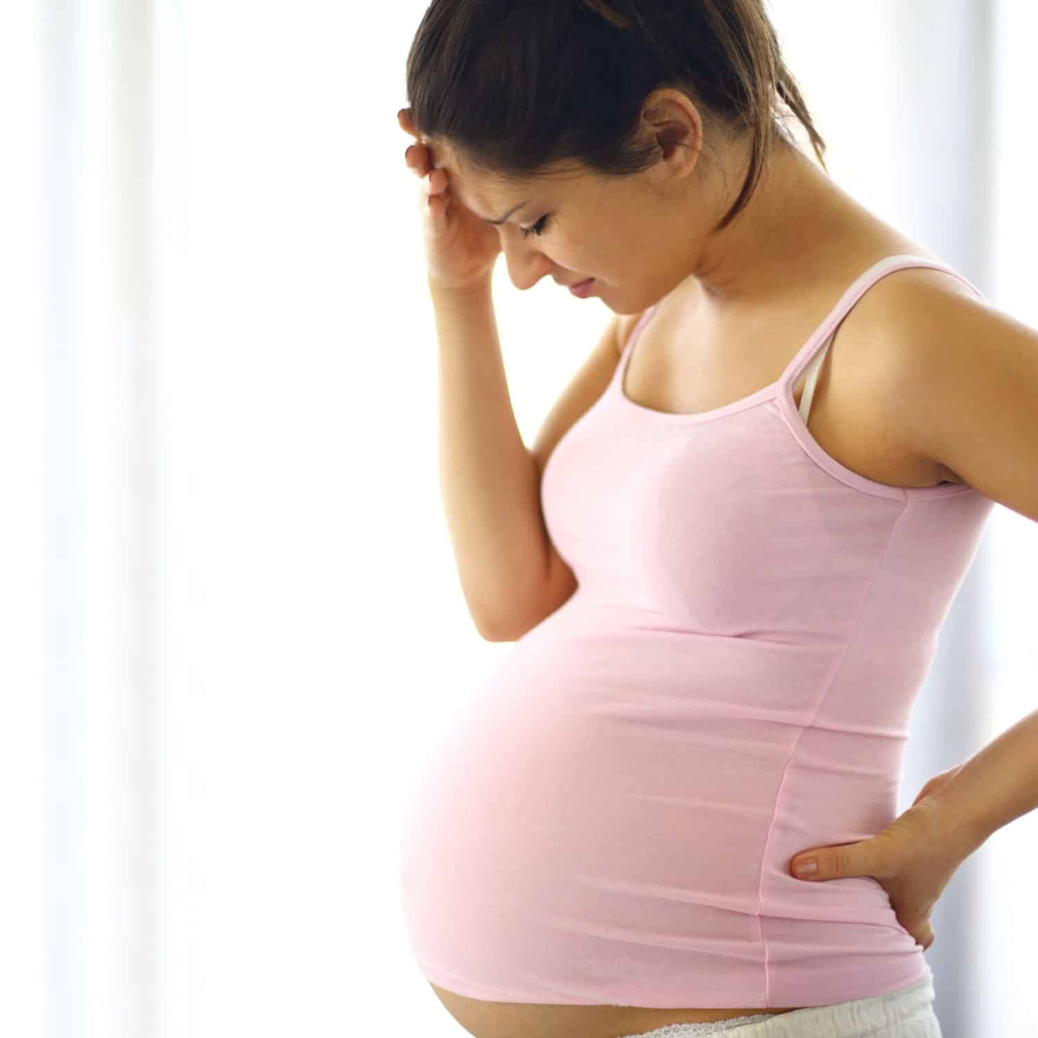 Woman dealing with head and back pain brought on by pregnancy - fairfax prenatal chiropractor