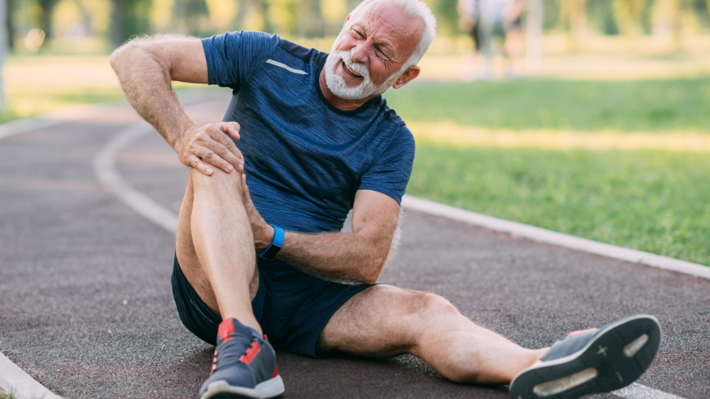 man sitting on the ground because his knee started hurting during exercise and he needs chiropractic care to treat his knee pain