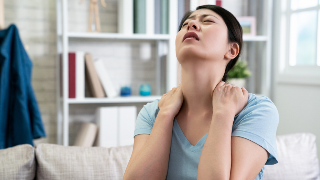 woman with neck pain after breastfeeding who needs to stretch using kaizo health's tops